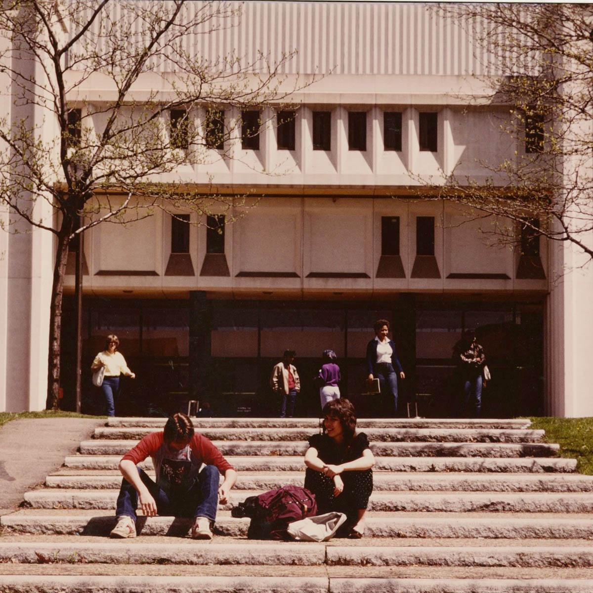 Vintage photograph from Chatham University archives of students circa 1970s seated on the steps of JKM Library